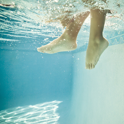 detail of kid feet on a  swimming pool - square format