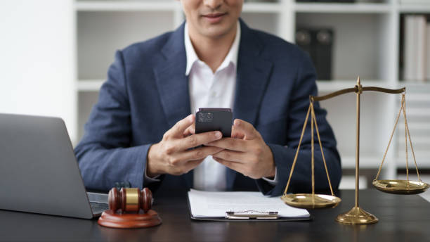 istock Young Asian legal officer working in his office room while having a phone call with his client. 1576207111