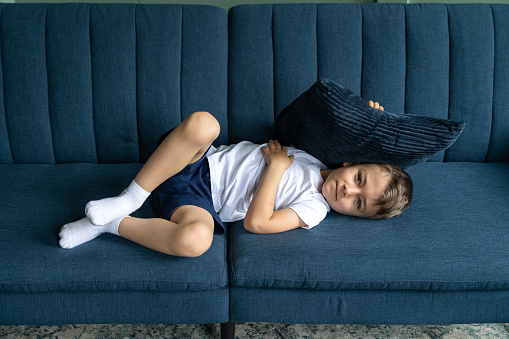 Portrait of a little boy. The boy lies on the couch with a small pillow.