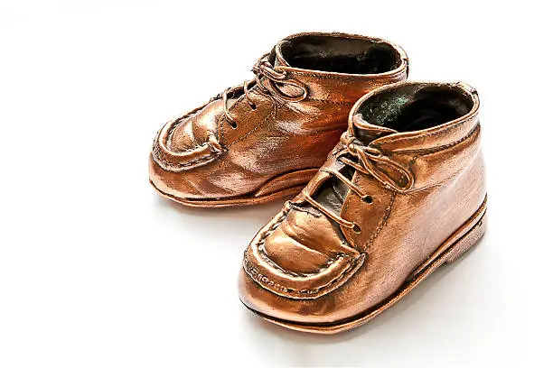 Babyshoes in bronze, on white background