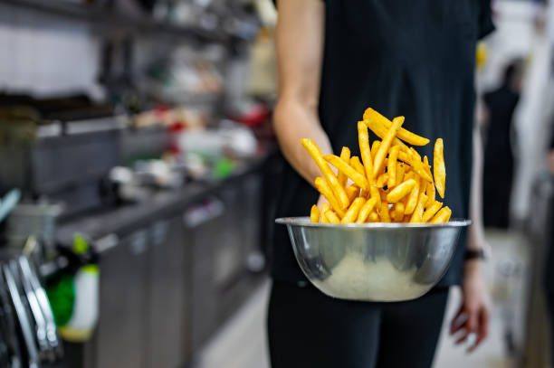 レストランのキッチンでフライドポテトを準備する女性シェフ - commercial kitchen chef cooking food service occupation ストック��フォトと画像