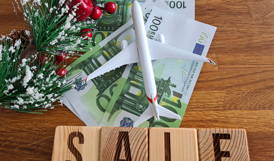 Airplane on European Union euro banknotes New Year and Christmas discount sale text. Prices for air tickets for travel and tourist business trips