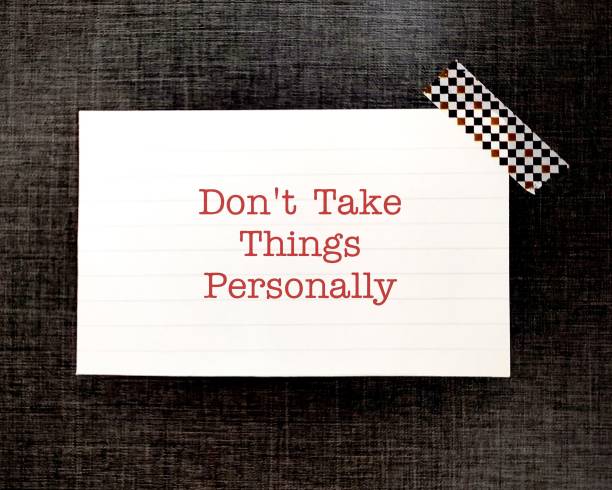 Note stick on black background DON'T TAKE THINGS PERSONALLY - means not to be offended or upset by what someone said, others insult you is about them, it has nothing to do with you
