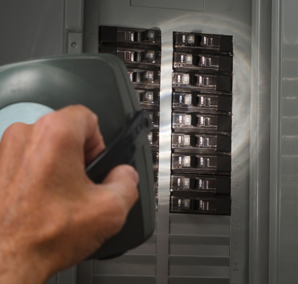 man examining circuit breakers at residential service panel