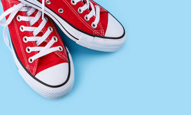 istock Red sneakers on blue background with copy space. Youth shoes. 1576233489