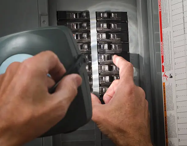 Photo of man with flashlight at residential circuit breaker panel