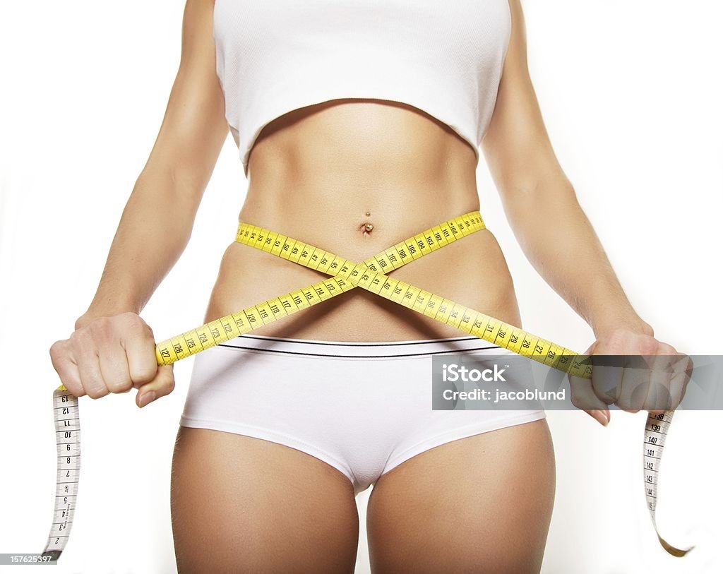 Tape Measure Around a Woman's Stomach Closeup of a woman's waistline with a tape measure around her flat stomach Dieting Stock Photo