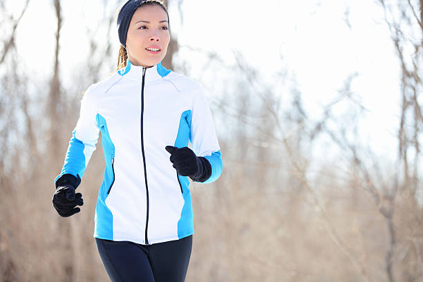 Young Asian woman jogging Running young Asian woman jogging in a winter fleece and gloves in open countryside with copyspace in a health and fitness concept. fleece photos stock pictures, royalty-free photos & images