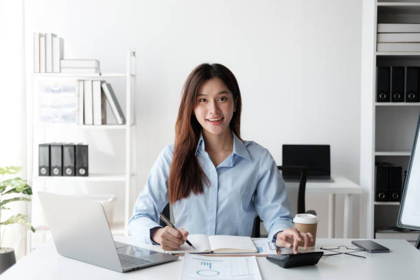 istock Young Asian accountant working on her project, calculating the budget, working in the office room. 1576270015