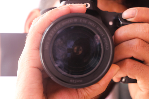Close up of photographer hands holding DSLR camera. Selective focus.