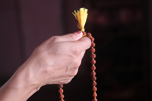 Selective focus of a chanting hand with rudraksha beads.