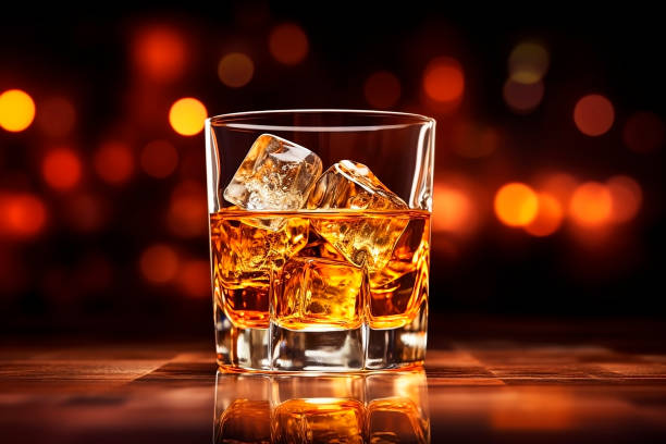 Whiskey with ice cubes in glass Whiskey with ice cubes in glass on background of lights. cognac brandy stock pictures, royalty-free photos & images