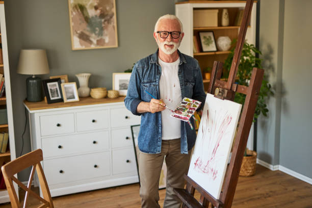 istock Elderly man painting on a canvas at home 1576306899