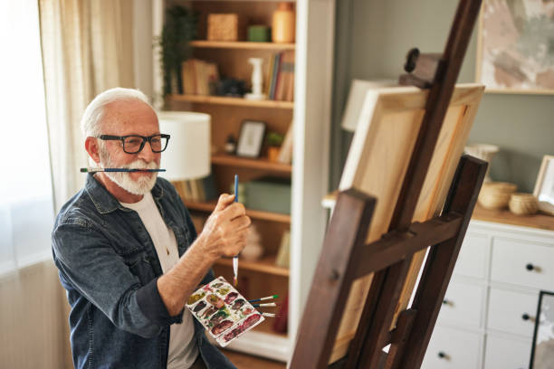 istock Elderly man painting on a canvas at home 1576307447