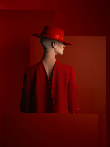 Back, fashion and mockup with a woman on a red background in studio for marketing, advertising or branding. Hat, aesthetic style or a trendy young female person standing with an empty or blank poster