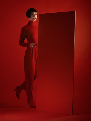 Fashion, mockup and a model woman in a red background in studio for marketing, advertising or branding. Luxury, aesthetic style or a trendy young female person standing with an empty or blank poster