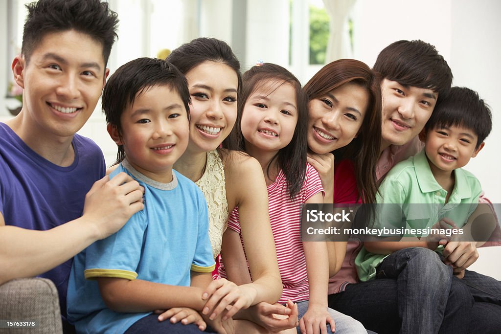 Due famiglie cinesi per sedersi e rilassarsi sul divano insieme - Foto stock royalty-free di Famiglia multigenerazionale