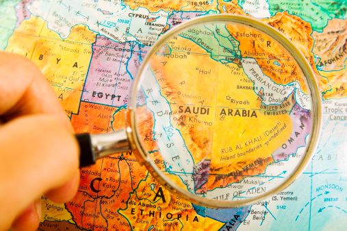 Studying Geography - Looking through magnifying glass at Saudi Arabia on a globe. 