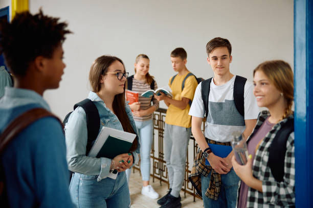 istock Happy high school friends communicating in hallway after a class. 1576359704