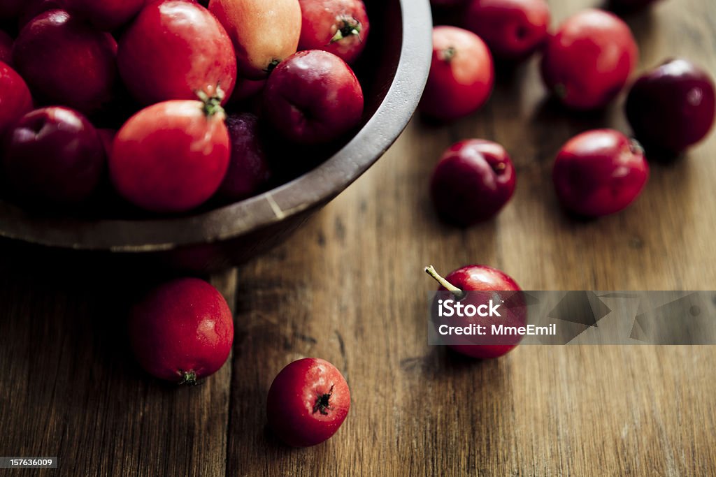 Crabapples Many crabapples in a bowl and on a wooden table. Selective focus on foreground. Natural light. Ingredient Stock Photo