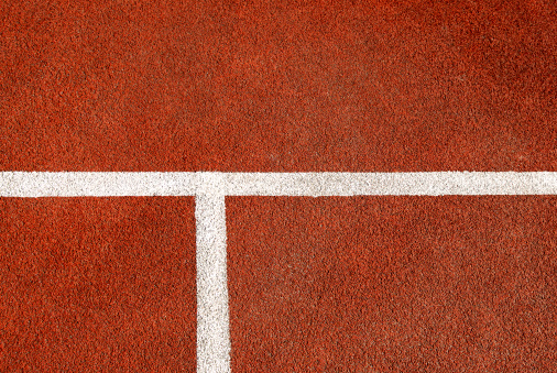 White line markings on a red tennis court.