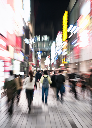 Zoom blur on crowds of pedestrians walking in Tokyo's Shinjuku area.