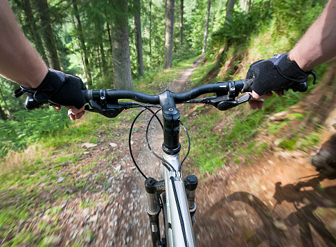 Motion blur as a mountain biker speeds down a woodland trail, photographed on the moving bike.