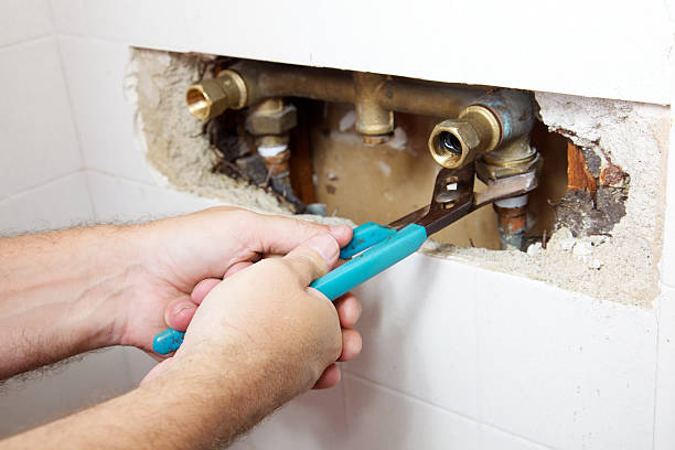 Shower Leak Plumber's hands have a two fisted grip on a wrench as he loosens a nut to fix a leak in a shower leaking stock pictures, royalty-free photos & images