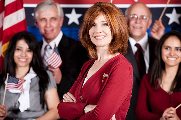 Female Politician Portrait of an attractive, confident, happy adult politician woman with her supporters in the background. political rally photos stock pictures, royalty-free photos & images