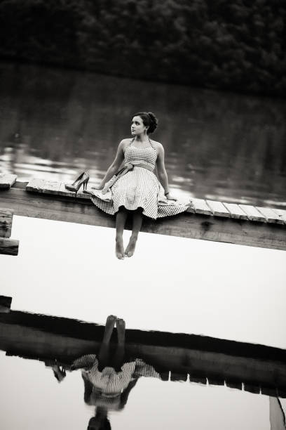 15 year old hispanic girl photo session wearing a vintage dress seating on a small pier, miami.