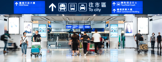 Motion blur of Asian tourist traveler people walk with luggage at Hong Kong international airport exit gate. Oversea transportation, airline transport business, Asia travel lifestyle concept