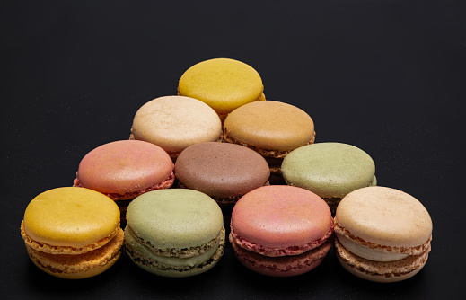 Macarons in a triangl shape isolated in a black background.