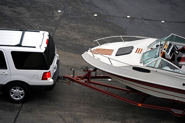 White SUV pulling white speed boat on trailer from above stock photo
