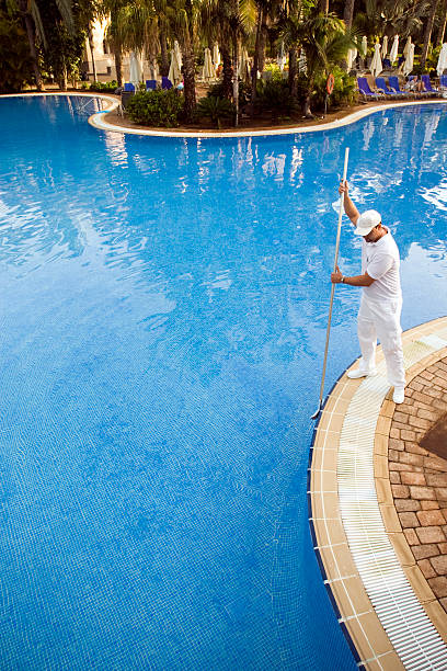 Male pool cleaner cleaning a blue pool stock photo