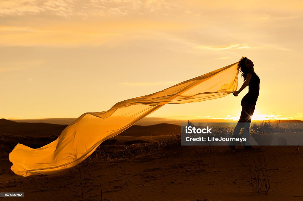 Mulher com lenço longo ondulado leve com cenário do pôr-do-sol - Foto de stock de Material Têxtil royalty-free