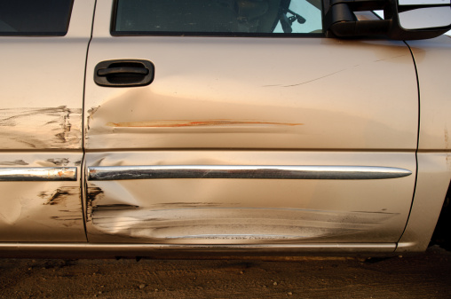 The side panel of a full size american made pickup truck with damage to both side doors