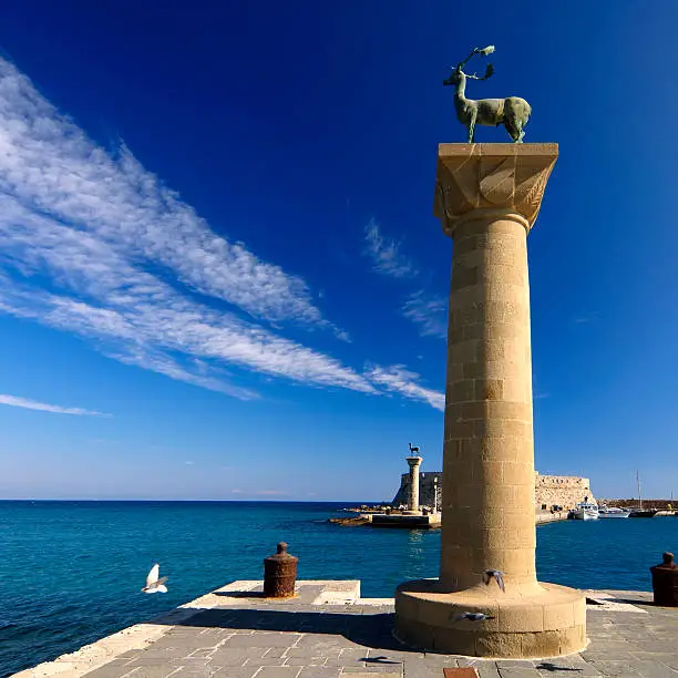 Rhodes island landmark, Port entry, Mandraki. The medieval lighthouse fort (at the background), and the two deer statues believed to be the base of Colossus, one of the 7 wonders of the ancient world. 