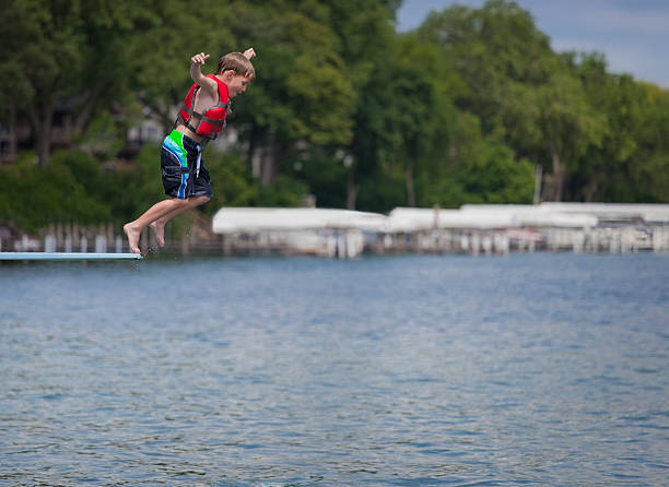 giovane ragazzo di tuffarsi in lago - life jacket little boys lake jumping foto e immagini stock