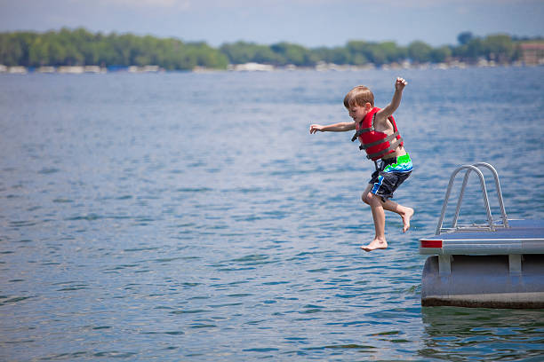 giovane ragazzo di tuffarsi in lago - life jacket little boys lake jumping foto e immagini stock