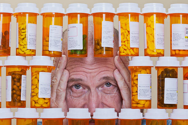 Depressed Senior Man Looking Through Rows of Prescription Medication stock photo