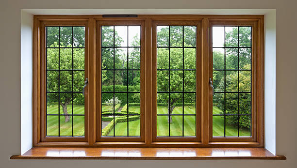 Garden view through leaded glass window A high quality leaded glass window made from solid mahogany from an expensive new house. The view through the window is towards a beautiful English garden with lawn and apple trees. Taken at the end of the day under an overcast sky and carefully lit for a balanced exposure of frame and the garden view. wood windows stock pictures, royalty-free photos & images