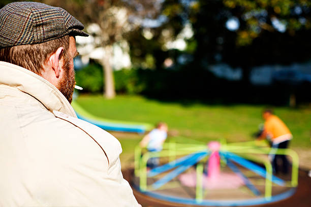 é este um pedophile? homem a olhar para as crianças no parque infantil - paedophilia imagens e fotografias de stock