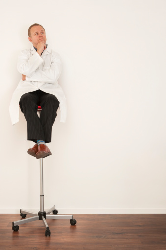 Tongue-in-cheek shot of professor/scientist/doctor aloft on an office chair in front of a blank whiteboard, ready to take your message.