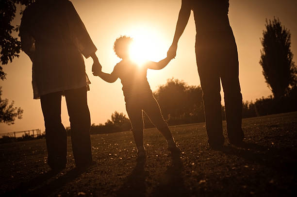 silhouette d'enfants tenant sa mère et de sa grand-mère les mains - generation gap multi generation family vertical holding hands photos et images de collection