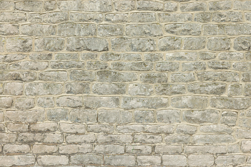 Old stone wall on the exterior of a house in UK. Full frame pattern or texture of wall made of sandstone blocks
