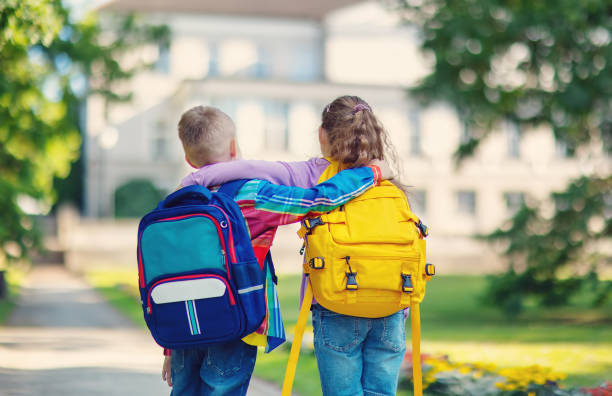 Boy and girl standing and hugging in the park near the school. stock photo