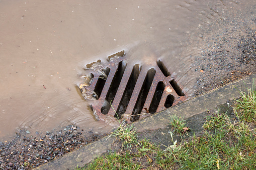 Rainwater flowing down a road drain after heavy rain, UK