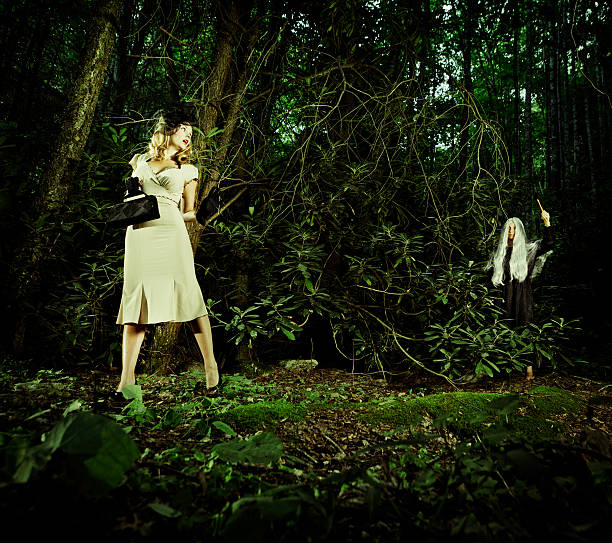 terrified woman dress with 40s style clothing walking thru the forest, and chase by a creepy woman dress like a witch behind her with an ax - shoot in the appalachian mountains - usa