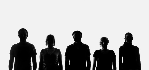 Five silhouettes of people standing in a row and posing for a picture. Studio shot on the white background.