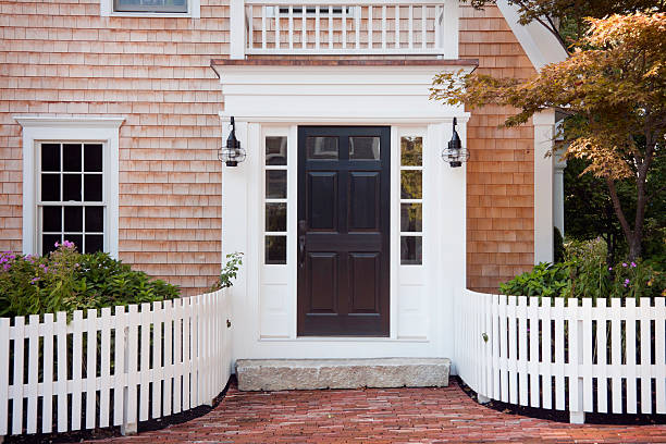 Entryway of brick New England home with picket fence A New England doorway on Cape Cod, Massachusetts in midsummer. front door stock pictures, royalty-free photos & images
